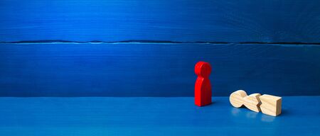 A figurine of a red man stands over a fallen split man. The concept of mutual aid, first aid. Social protection and caring. Psychological and physical rehabilitation. banner, place for textの写真素材