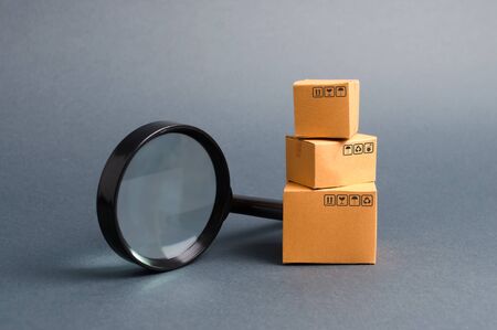Cardboard boxes and a magnifying glass. Warehouse of finished products and equipment. buying and selling goods and services, internet commerce, online shopping, trade and turnover. Import and exportの写真素材