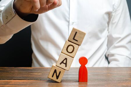 Man pushes downs a cube tower with the word Loan on the red man figure. Lack of protection for vulnerable groups of the population. Debt pit. Harassment of the borrower by collectors. Threat of lifeの写真素材
