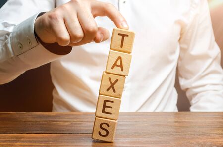 The man does not allow the tower to fall out of the book with the word Taxation. Heavy tax burden, Reducing the burden on business. protecting the interests of small and medium-sized businessesの写真素材