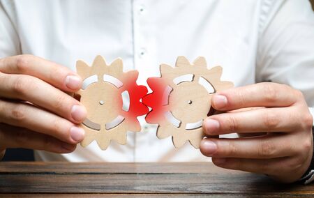 A businessman tries to put two gears together and fails to make them work. The concept of the impossibility of effective business processes, high costs and low returns. Wrong business model.の写真素材