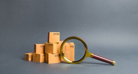 A pile of boxes and a magnifying glass. Concept search for goods and services. Tracking parcels. Quality control. Services for searching, comparing products from different trading companies.の写真素材