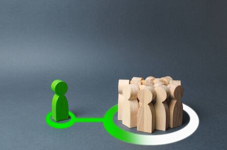 A green human figure influences a crowd of people. presentation of a new idea or thought and bringing people to your side. Distribution of information through social networks. Cooperation, assistanceの写真素材