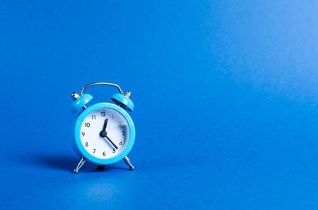 A blue alarm clock on a blue background. Limited offer and over time. Planning and discipline....