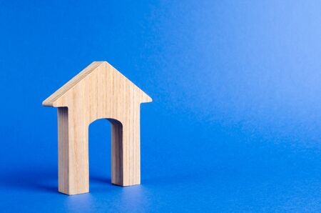 Wooden figure of a house with a large doorway on blue background. concept of buying and selling real estate, rent, investment. Home, Affordable housing, residential building. Construction buildings.の写真素材