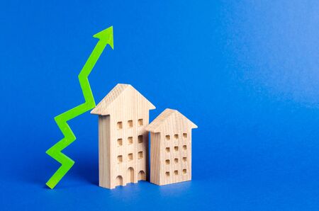 figures of residential buildings and green arrow up. Increasing cost and liquidity of real estate. Attractive investing. rising prices or renting. growth of supply and demand, high rates of sales.の写真素材