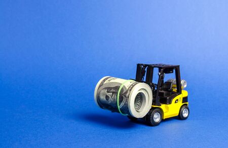 Forklift truck carries a bundle of dollars. Attracting direct investment in business and production, improving economic performance. capitalism. Export of capital, offshore economic zones.の写真素材