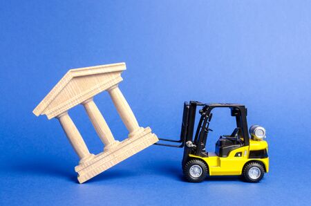 Yellow forklift overturns a government building. Bank, museum, monument of architecture. Dismantling power, protests and revolutionary sentiment. Destroying the old to build the new. Saving historyの写真素材