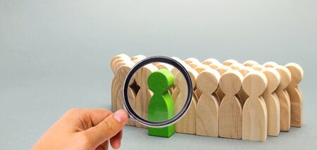 Green man coming out of the crowd. The chosen person among others. A talented worker. Promotion. Concept of search for a worker. The dismissal of an employee. Demotion. Human Resource. selective focusの写真素材