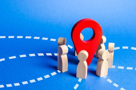 People gathered around the red navigation pointer pin. Meeting place concept. A long awaited meeting, a company of friends, acquaintance via the Internet. Event or holiday. Organization of joint tripの写真素材