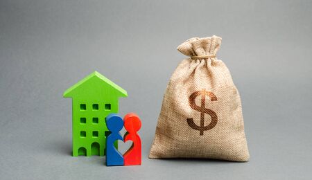 Money bag and family standing near the house. The concept of money management and property. Budget planning. Accumulation of money for a home or apartment. Mortgage, taxes and debts. Creditの写真素材