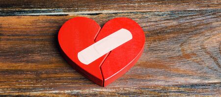 A red heart with a plaster. Renewal of the relationship. Family psychotherapist services. Reconciliation. Saving the family. Search for compromises. Conflict, dispute resolutionの写真素材