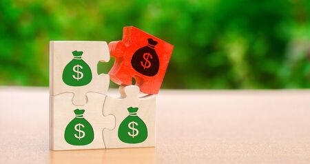 Wooden puzzles with the image of money. Withholding money and commission. Tax and taxation. The taxes burden. Net income. Costs. Ebitda. Business and Finance. Profit management. Investmentsの写真素材