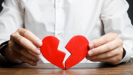 A man collects a broken heart in his hands. Concept of love and relationships. Family psychotherapist services. Reconciliation. Saving the family. Search for compromises. Search for the second half.の写真素材
