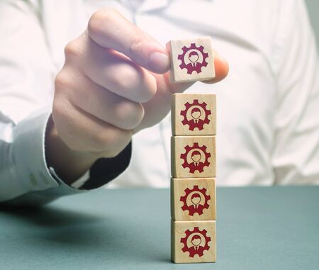 The leader puts wooden blocks with the image of workers. Team management concept. Working staff....
