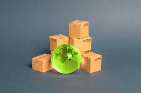 Green glass planet globe and a pile of cardboard boxes. Business and industry, transport...