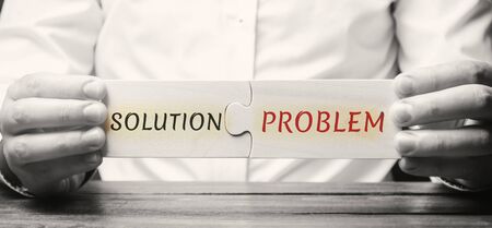 Businessman collects wooden puzzles with the word Solution problem. A strategy for overcoming business problems and difficulties. Concept motivation. Achieving the goal. Decision-makingの写真素材