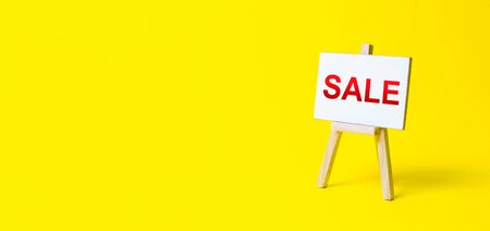 Easel sign with the words Sale. Advertising marketing. Discount. Shopping online. Increase sales and attract new customers. Sale of goods and products by attractive prices and promotions.の写真素材
