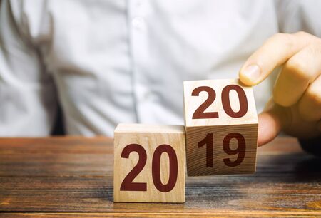 Two wooden blocks with numbers 2019 and 2020. The concept of the beginning of the new year. New objectives. Next decade. Trends and changes in the world. Build plans and goals. Time reportの写真素材