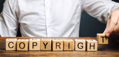 Businessman puts wooden blocks with the word Copyright. Patenting. Copyright protection. Brand and...