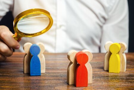 Groups of multicolored wooden people and businessman. The concept of market segmentation. Target audience, customer care. Market group of buyers. Customer relationship management. Selective focusの写真素材
