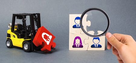 A magnifying glass looks at a red puzzle to the unfinished assembly of business team. Search, recruitment staff, hiring leader. Creating an efficient and productive business unit. Leadershipの写真素材