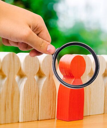 Wooden figures of people. The red man comes out with a team of workers. The concept of choosing a new leader. Choice of person. Hiring and recruiting. Human resource management. Selective focusの写真素材