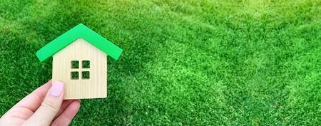 Miniature wooden house on green grass. Real estate concept. Eco-friendly and energy efficient house. Buying a home outside the city. The urban downshift. Nature. Fresh air. Mortgage, loan. Propertyの写真素材
