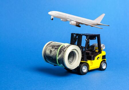 Forklift truck carries a bundle of dollars and airplane. Export of capital, offshore economic zones. Attracting direct investment in business and production, improving performance. capitalismの写真素材