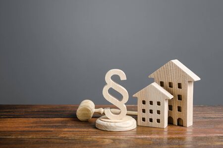 Wooden houses and paragraph figurine with judge hammer. Litigation in housing and real estate disputes. Norms and rules for construction, maintenance. Encouraging green and energy-saving technologiesの写真素材
