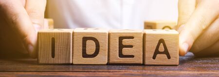 Businessman puts wooden blocks with the word Idea. Generation of innovative business ideas. Creative...