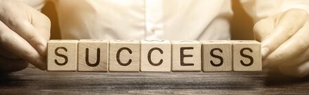 Wooden blocks with the word Success and businessman. Successful business concept. Achieving the goal, overcoming difficulties. The growth of profits and earnings in the company. Performanceの写真素材