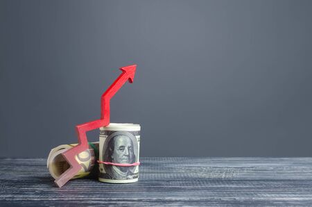 Money bundle rolls and red up arrow. Revenue profit rise. Favorable deposits. Cheap loans for economic growth business development. High profits, superprofits. Investments. Wealth and prosperityの写真素材