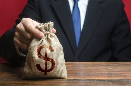A man holds out a bag of money. Bank deposit. Donations. Financial social assistance. Provision of money on credit, grant. Project financing. Payment purchases, profits dividends. Business investment.の写真素材