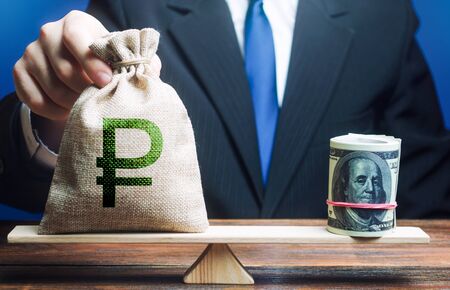 Man puts a russian ruble money bag on scales opposite to dollar bundle. Monetary policy. Central...