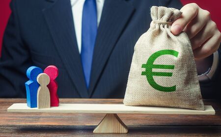 Man puts euro money bag on scales with family figures. Charitable donations, invest in human capital. Social assistance, financial support for who in need, vulnerable populations. Help aid migrantsの写真素材