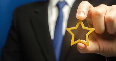 Man holds a golden star in his hand. Symbol of success and excellence. Good reputation, prestige,...