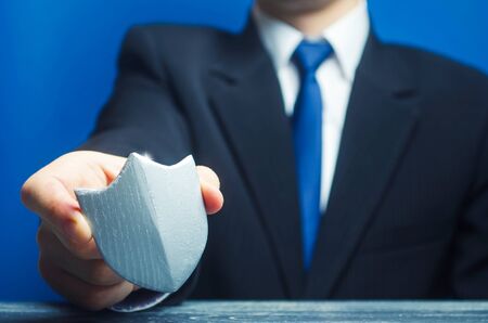 A man holds a protection shield in his hand. Safety, life and property insurance. Security personnel, maintaining law and order. Lawyer defends the rights and innocence. Protectionism, defenseの写真素材