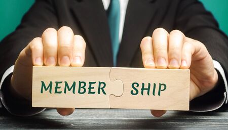 Businessman collects wooden puzzles with the words Membership. Belonging of people to the organization, society, association. Business conceptの写真素材
