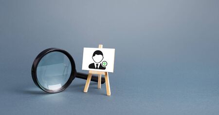 Magnifying glass and an easel with a new hired employee. Recruiting and HR management. Hiring new workers, staffing. Headhunters and Human Resources. Search for skilled specialists and professionals.の写真素材