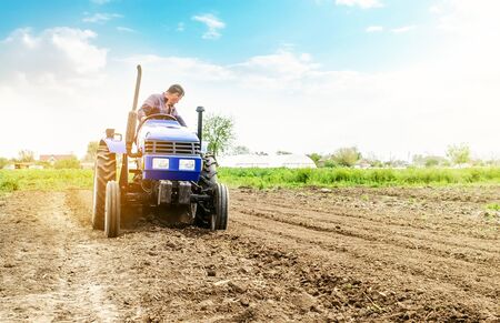 Farmer is processing soil on a tractor. Soil milling, crumbling mixing. Loosening surface, cultivating land for further planting. Agriculture, growing organic food vegetables. Agroindustry, farming.の写真素材