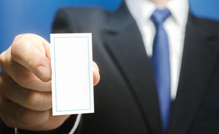 Businessman introduces himself with a vertical business card. Presentation, hands over contacts to client. Business advertising. Attracting new customers. Agent offers his services. Solidity and styleの写真素材