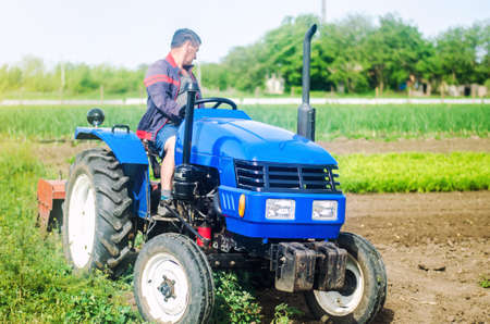 A farmer drives a tractor while working on a farm field. Loosening surface, cultivating the land....