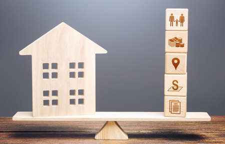 House and blocks of real estate requirements criteria parameters on scales. Searching for a suitable house by criteria. Best choice on market. Realtor services. Price, area, location infrastructure.の写真素材