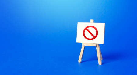 Easel with the prohibition sign NO on a blue background. Restricted area. Restrictions and Sanctions. Out of stock. Ban and Embargo. Failed strategy. Inaccessibility, taboo. Blocking.の写真素材