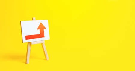 Easel with a red right up arrow. Direction to go around. Bypassing obstacles and solving problems. Alternative way. Attract attention. Advertising sign, marketing. Change of route. Copy spaceの写真素材