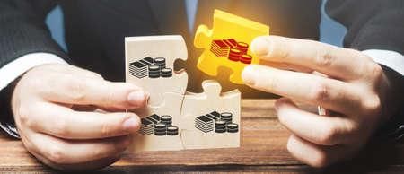 Businessman holds the wooden puzzle with a picture of money. The concept of financial management and...