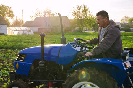 A farmer on a tractor drives across the farm field. Agro industry, agribusiness. Potato harvest...