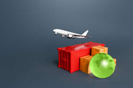 Cargo plane over a container with boxes and a globe. Services of express delivery and transportation of goods by plane. Business and commerce, import export of products. World trade and logistics.の写真素材