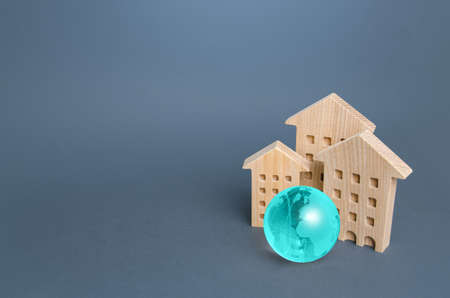 Residential buildings and blue globe. Environmentally friendly housing, minimal impact on environment. Energy efficiency, zero carbon emissions. Carbon neutrality. Internet service communication. IoTの写真素材